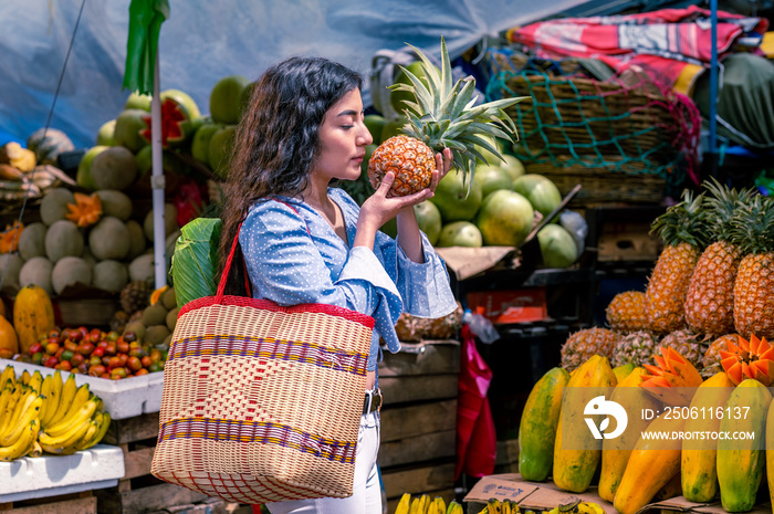 Hermosa Mujer latina en medio de un mercado de frutas frescas, con una canasta sostiene en sus manos