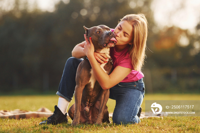 积极的情绪。穿着休闲服的女人在户外和比特犬在一起