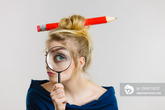 Woman holding magnifying glass having hair pencil