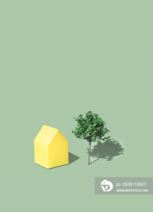 Minimal residential real estate concept with a town house and a tree on a illuminating yellow backgr