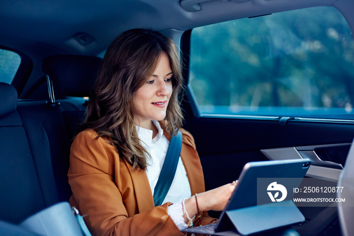 Caucasian woman working from the back seat of a car - Business woman using a laptop