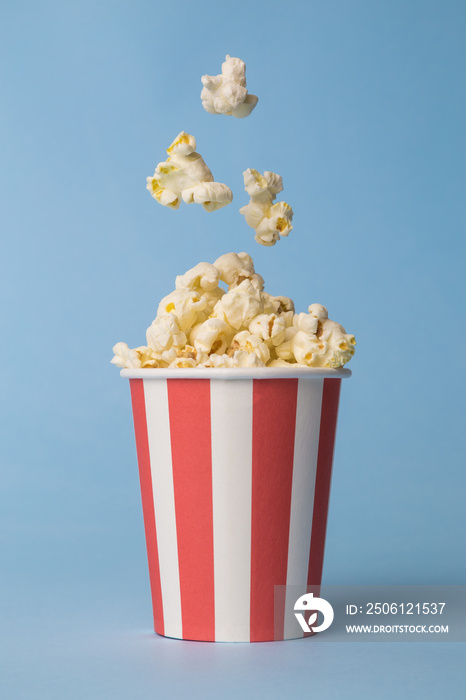 Falling popcorn in box isolated on blue.