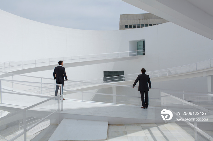 Businessmen on sunny modern courtyard ramp