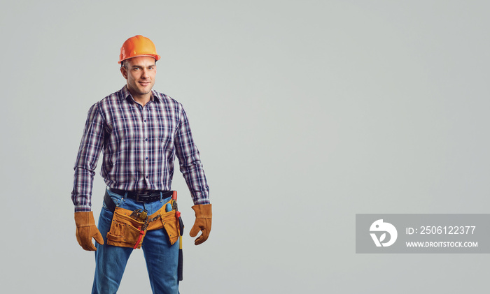 Male builder in  helmet in a plaid shirt smiling