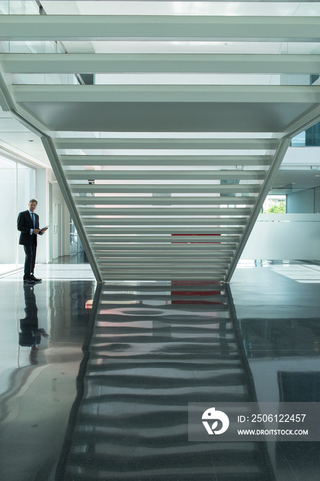 Businessman in modern office lobby with staircase