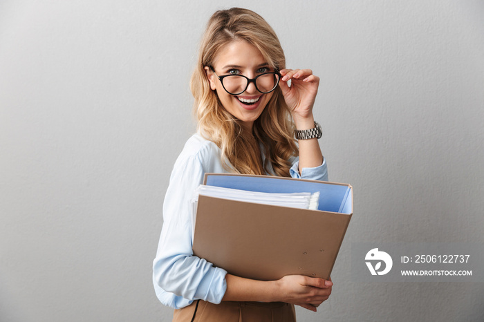 Photo of adorable blond secretary woman wearing eyeglasses smiling and holding file folder while wor