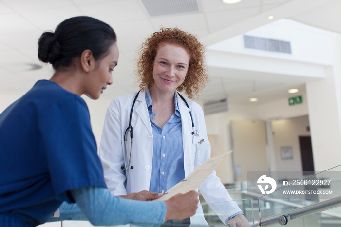 Portrait confident female doctor consulting with nurse in hospital