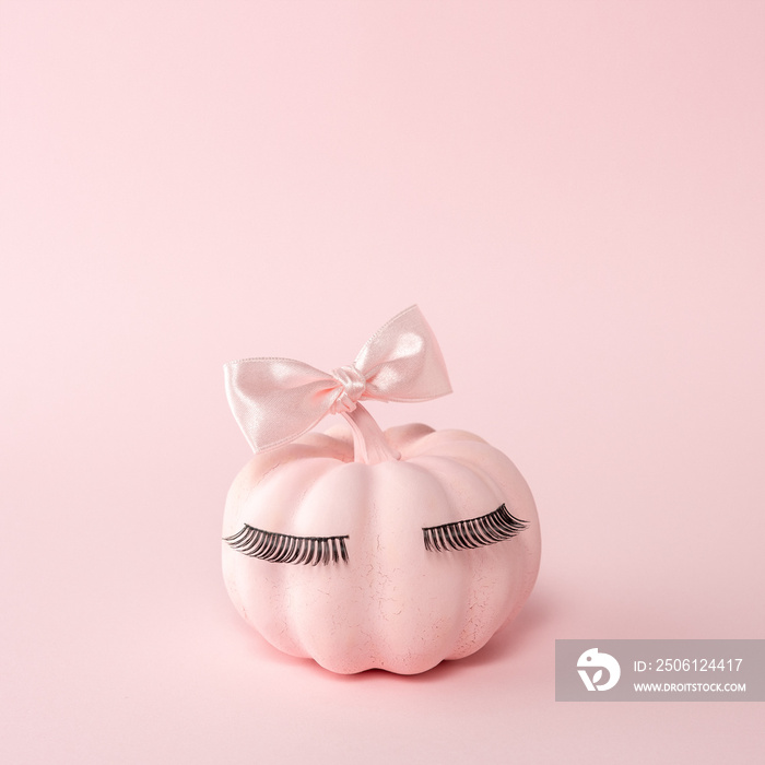 Pink Halloween pumpkin with pink bow tie on a pink background. Minimal Halloween spooky girl concept