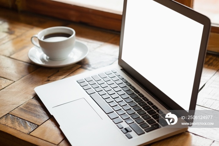 Close up of digital laptop by coffee cup on wooden table