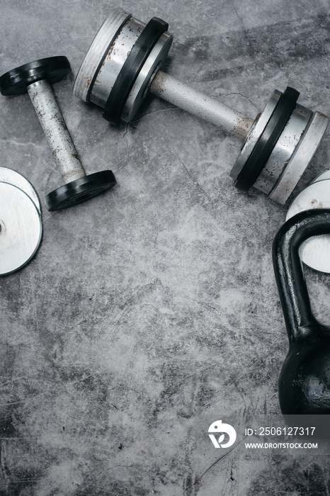健身或健美概念背景。灰色混凝土地板上的旧铁哑铃和壶铃