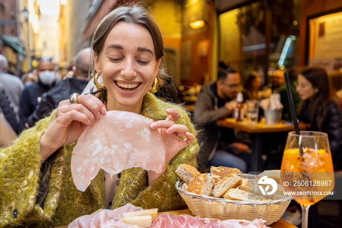 博洛尼亚市一名女子在户外酒吧吃着肉盘，玩得很开心。女孩抱着mortadella，fam