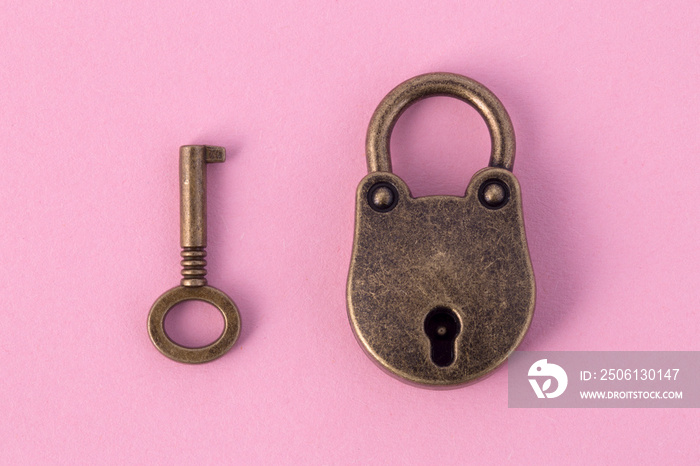 bronze key and padlock on gently pink paper, background image