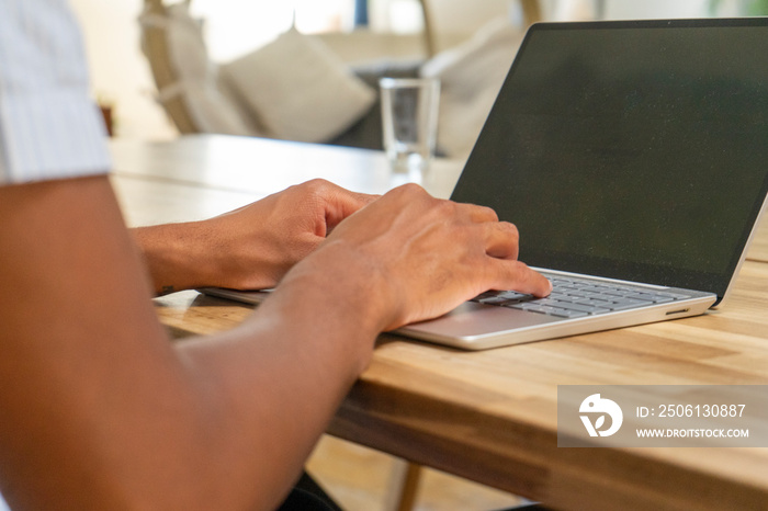 UK, London,�Close-up�of hands of man using laptop at wooden table