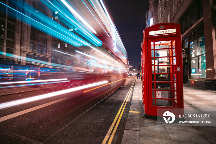 Light trails of a double decker bus next to the iconic telephone booth in London