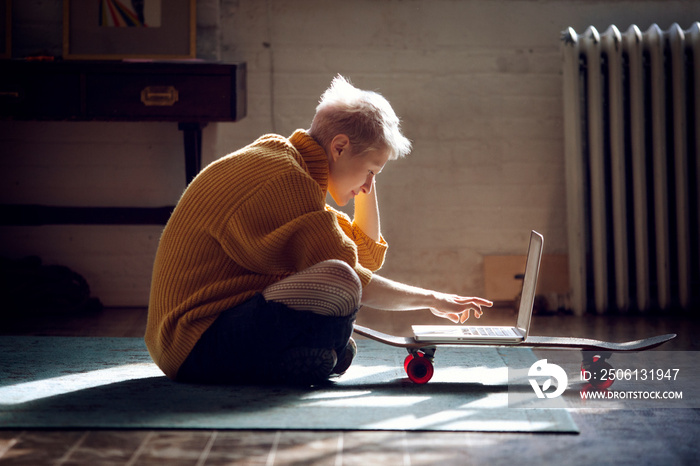 Side view of young woman using laptop in living room