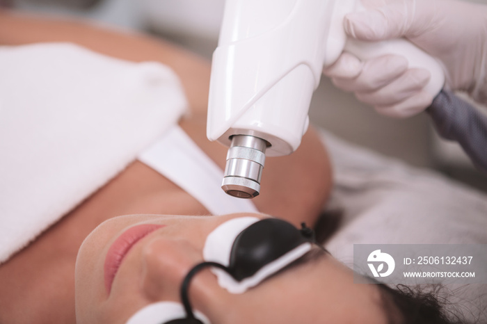 Cropped close up of a beautician doing facial hair laser removal procedure on a female client. Woman