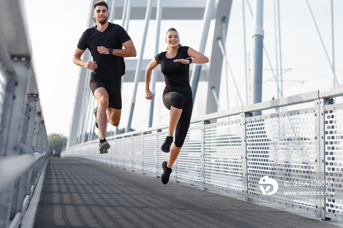 Young couple running outdoor on bridge. Young man and woman jumping together.