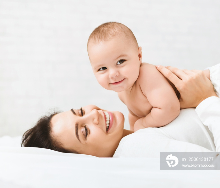 Mom and baby boy in diaper playing in bedroom