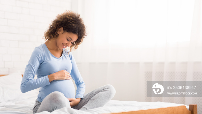 Cute afro pregnant woman caressing her belly