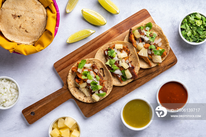 Traditional Mexican street food called  Tacos al pastor  prepared with pork, tortillas, pineapple, c