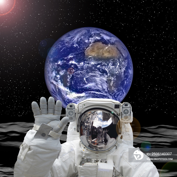 Astronaut posing on alien land. Earth on the backdrop. The elements of this image furnished by NASA.