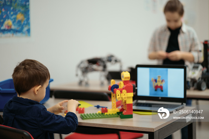 两个不同年龄的孩子在机器人学校选择机器人电动玩具的零件来制造机器人