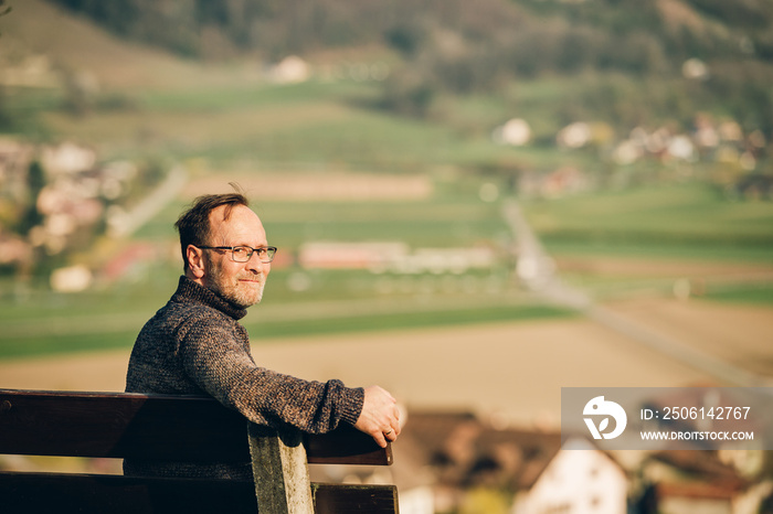 阳光明媚的一天，中年男子在长椅上放松，照片拍摄于瑞士瓦莱州