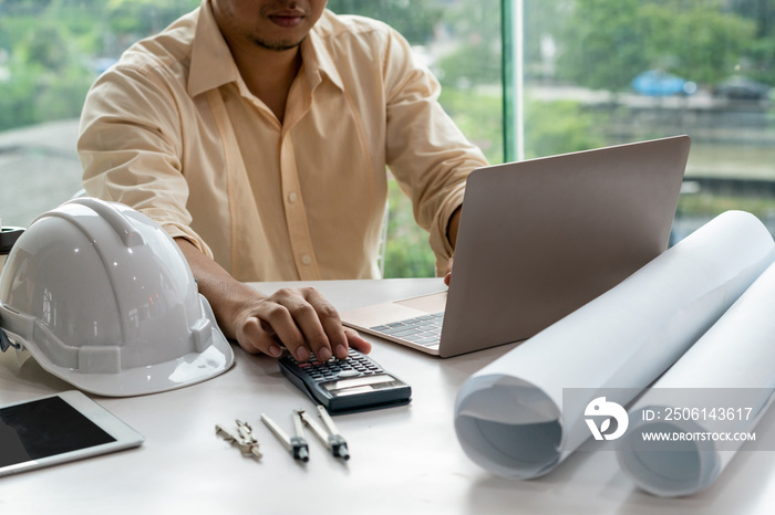 Young man architect or engineer working at desk with designer equipment to make interior design at w