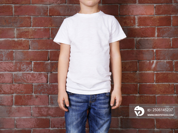 Closeup of boy in white T-shirt on brick wall background