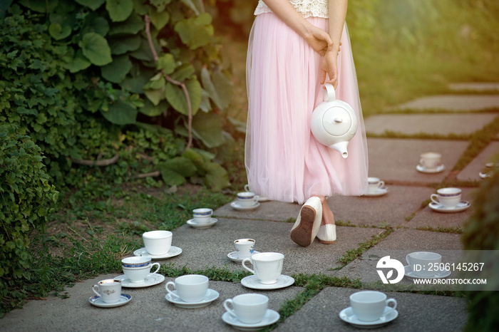 爱丽丝梦游仙境。一个穿着短裙的女孩，手里拿着茶壶，夹在一套杯子和酱汁中