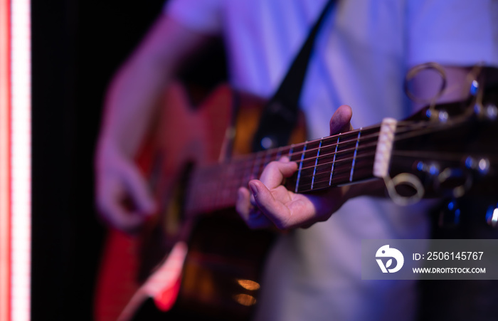 Close-up of a guitarists fingers while playing an acoustic guitar.