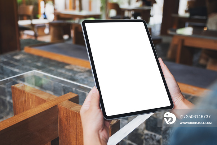 Mockup image of a woman holding digital tablet with blank white desktop screen in cafe