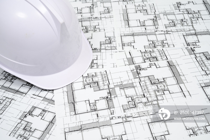 建筑业概念，在建筑图纸上戴上安全帽。