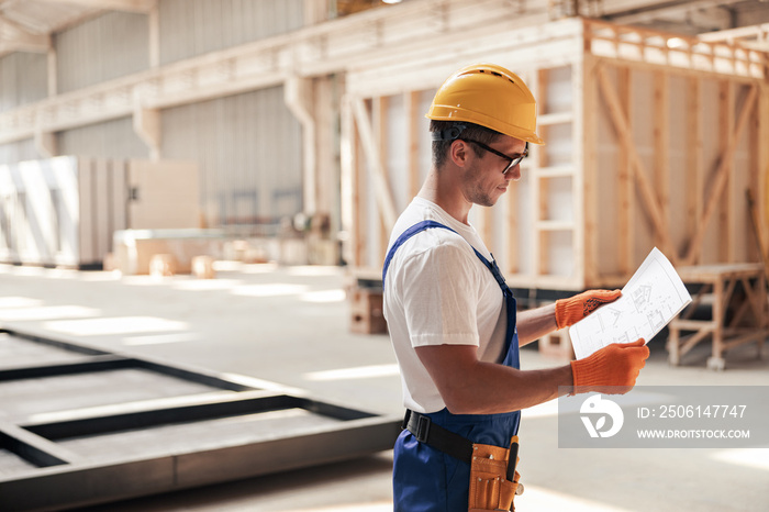 Male builder studying architectural plan at construction site