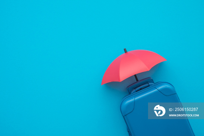 Travel insurance business concept. Red umbrella cover suitcases travelers on blue background copy sp