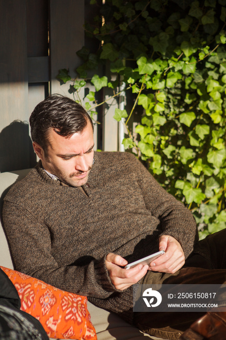 Man using cell phone in domestic garden