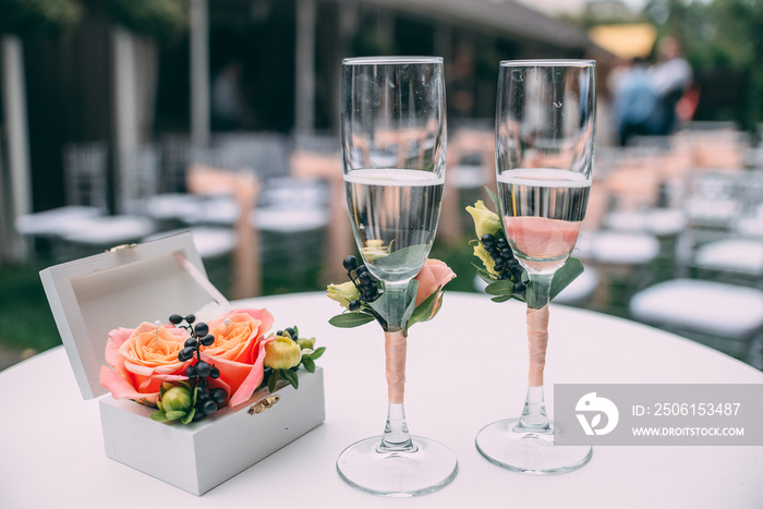 Two wedding glasses and bridal bouquet on stone in summer garden