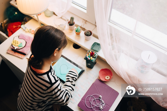 High angle view of girl drawing on digital tablet at table in bedroom