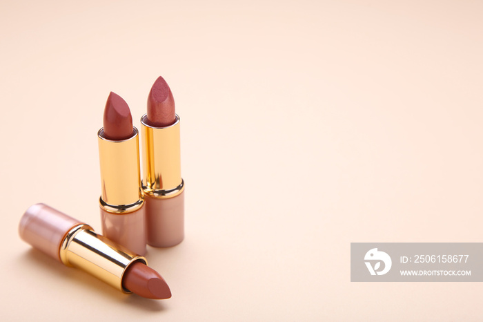 Brown lipsticks on beige background, make up