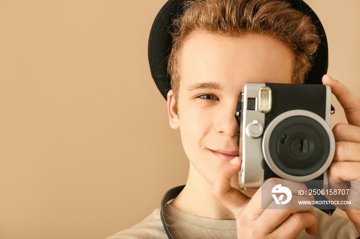 Teenage boy with photo camera on color background