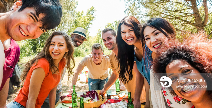 Happy friends eating and drinking beers at barbecue dinner at sunset - Group of people having meal t