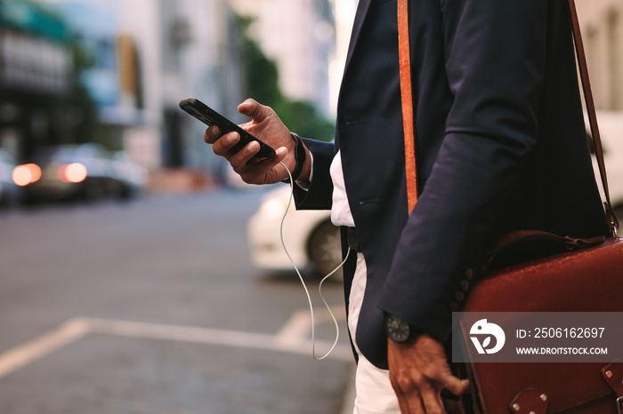 Businessman walking outdoors using mobile phone