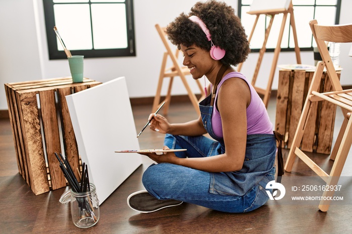 年轻的非裔美国妇女在艺术工作室听音乐画画