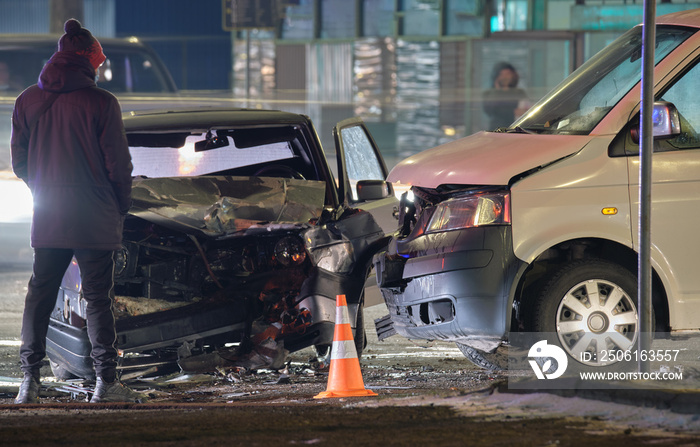 夜间城市街道上发生碰撞后，汽车在道路事故中严重碰撞，并有人侧影