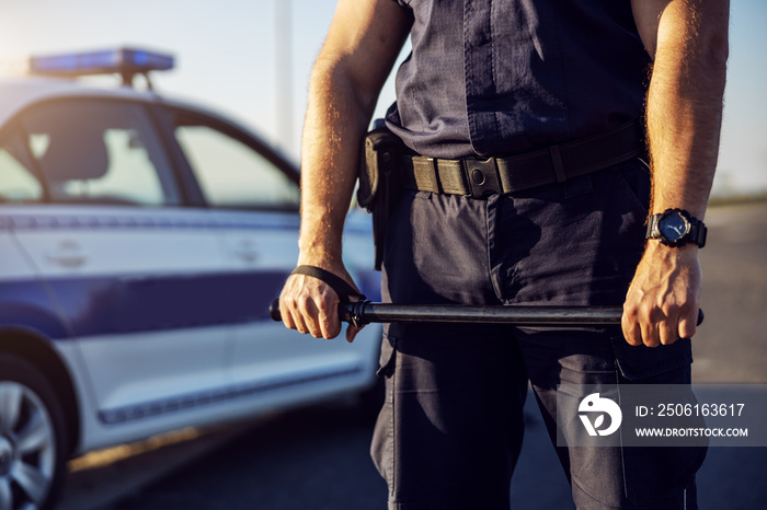 Police officer baton in hands. Policeman in action.