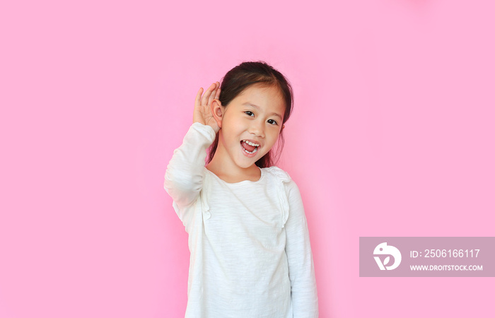 Attractive asian little kid girl smiling with hand over ear listening and hearing rumor or gossip ov