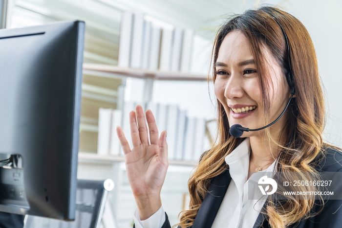 Smiling friendly asian businesswoman with headset working and greets interlocutor for online communi