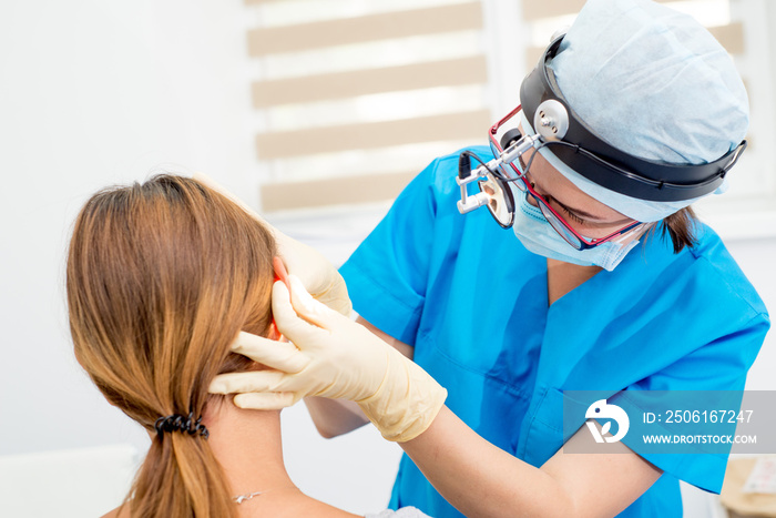 ENT doctor with tools, a mask and gloves examines the patients ears. Otolaryngologist with her.tool