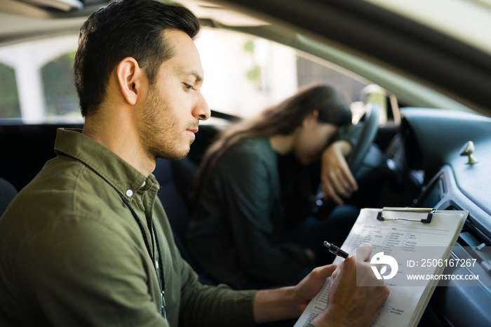 Instructor writing the bad grades of a teenagers driving test