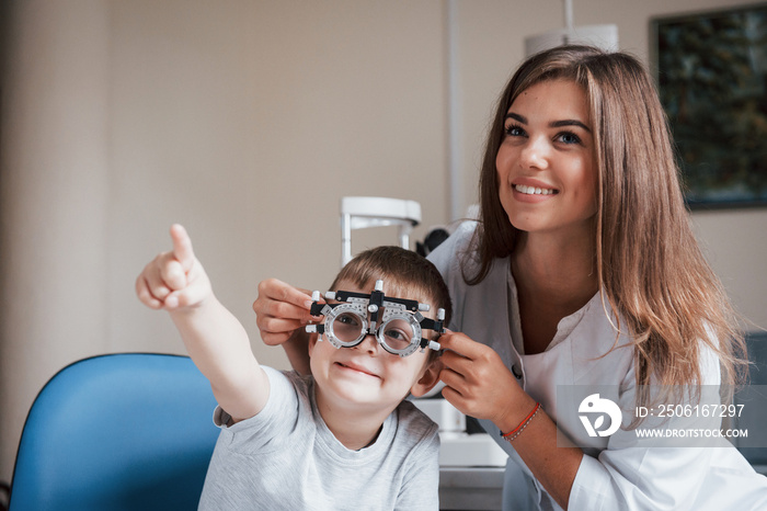 Both are watching to a board. Child sitting in the doctors cabinet and have tested his visual acuit